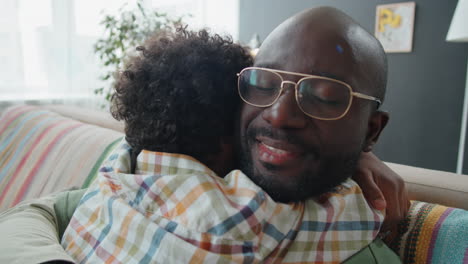 Loving-African-American-Dad-and-Little-Son-Embracing-on-Sofa-at-Home